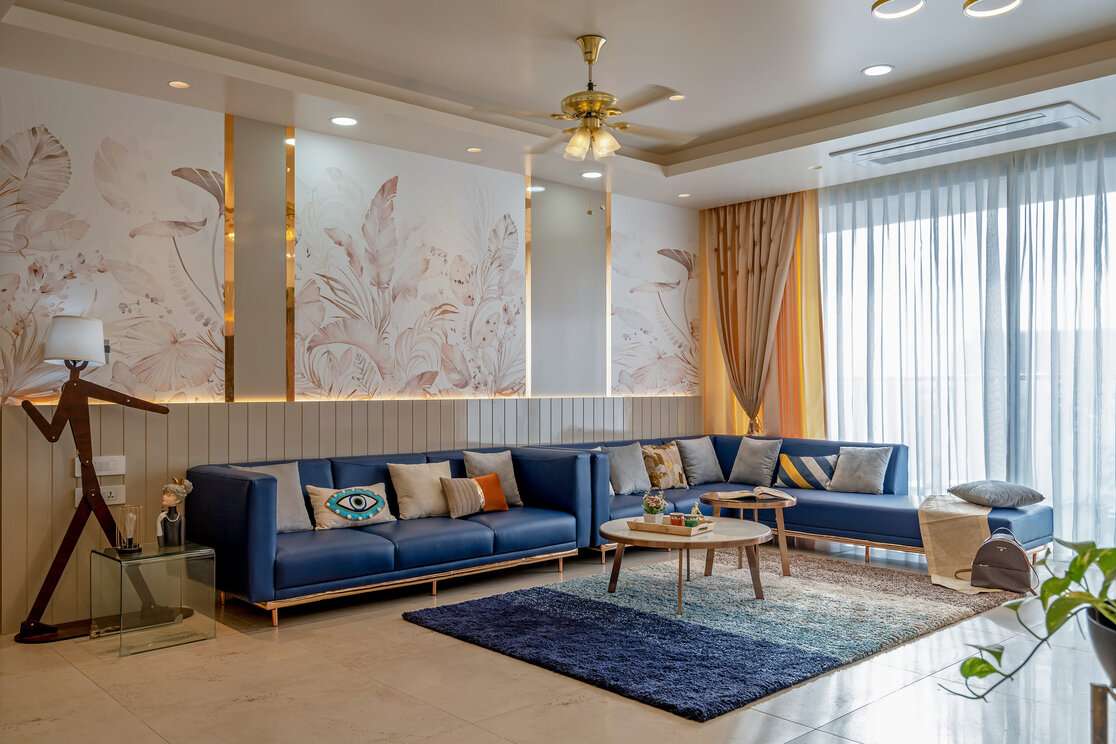 Stylish living room with blue sectional sofa, modern decor, large windows, and soft lighting.