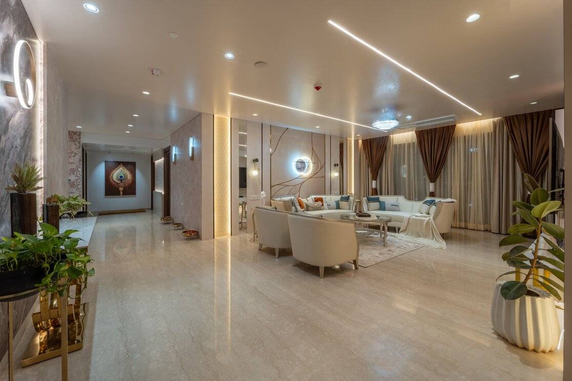 Luxurious living room with cream sofas, marble flooring, indoor plants, and elegant lighting.