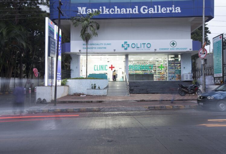 Front view of Manikchand Galleria with a clinic and pharmacy, located along a busy street.