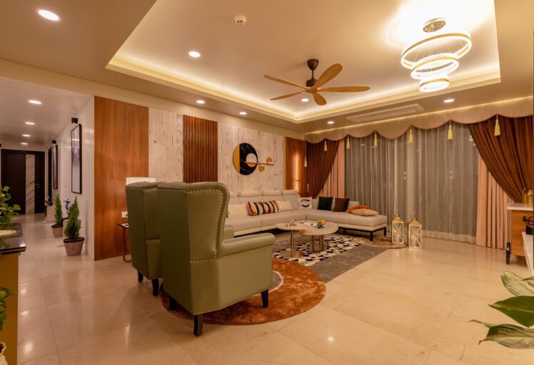 Elegant living room with green armchairs, beige sectional sofa, and warm ceiling lighting.