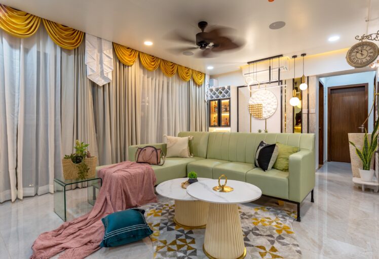 Colorful living room with green sofa, round coffee tables, golden drapes, and modern lighting.