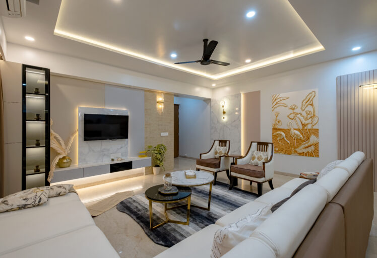 Modern living room with white sofa, accent chairs, TV unit, and warm ambient lighting.